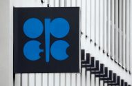 Sinal da OPEC em preto e azul, fixado em uma estrutura com barras verticais claras.