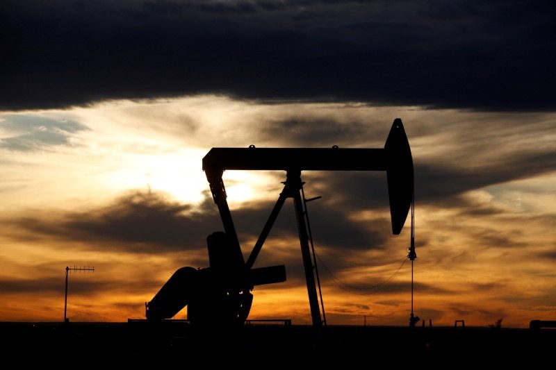 Bomba de petróleo em silhueta contra um pôr do sol laranja e nuvens escuras.