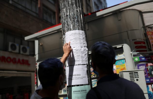 pessoas vendo cartaz com anuncios de emprego pregado em um poste na rua