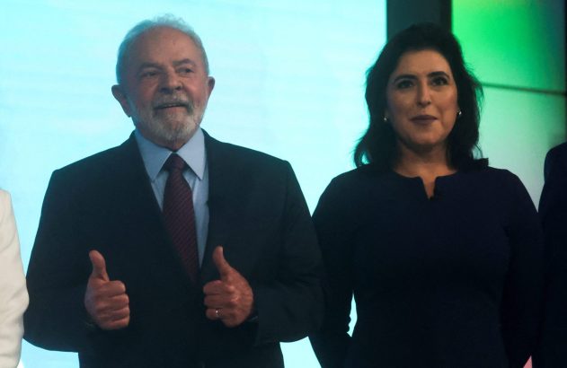 Lula e Simone Tebet sorriem. Lula faz sinal de positivo com as duas mãos.