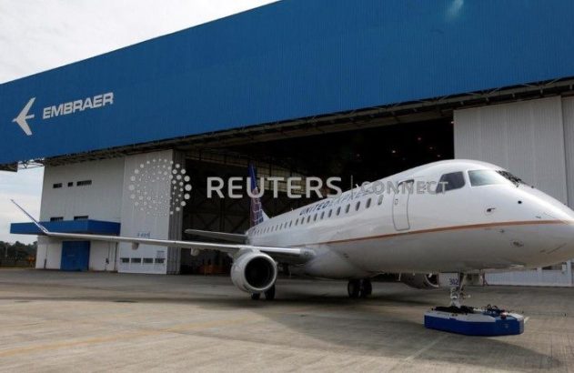 Jato regional branco United Express parcialmente fora de hangar Embraer azul.