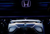 Carro-conceito Honda SUV e: Prototype branco com iluminação LED em exposição. Grande logo Honda acima.