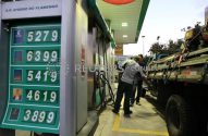 Pessoas abastecendo um caminhão em posto de gasolina Petrobras, com tabela de preços de combustíveis visível.