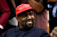 Kanye West sorri, usando boné vermelho "MAKE AMERICA GREAT AGAIN" e camisa escura.