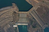 Vista aérea de usina hidrelétrica FURNAS. Represa, barragem e tubulações, com água liberada gerando energia.