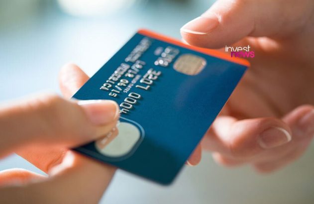 Mãos entregando um cartão de crédito azul com chip.