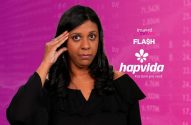 Mulher preocupada com a mão na testa, em fundo rosa com dados financeiros e logos de notícias/saúde.