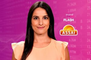 fabiana ortega, apresentadora do investnews, com logo do Assaí ao fundo