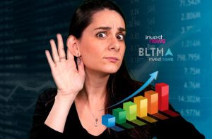 Mulher atenta, com mão na orelha, ouvindo dados de mercado financeiro com gráficos e "investnews" ao fundo.