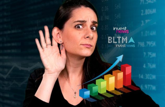 Mulher atenta, com mão na orelha, ouvindo dados de mercado financeiro com gráficos e "investnews" ao fundo.