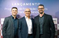 Três homens em frente a banner de lançamento de Programa de Formação. Logos Unyleya, Ito, AWS visíveis.