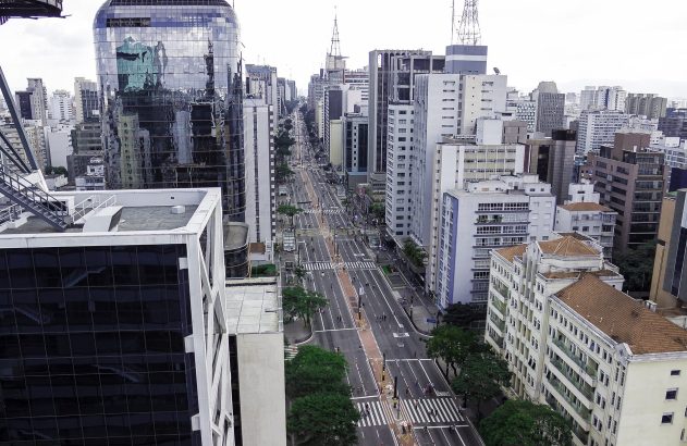 Vista aérea da Avenida Paulista em São Paulo, com edifícios altos e pessoas.