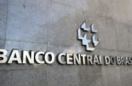 Sinalização metálica do Banco Central do Brasil com logo na parede de pedra.