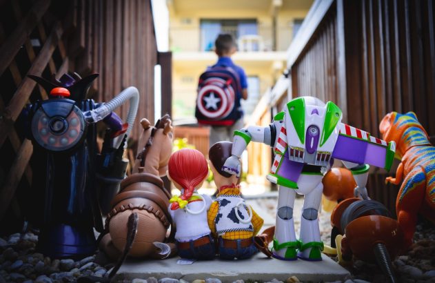 Brinquedos de Toy Story (Buzz, Woody, Zurg) observam menino com mochila Capitão América ir embora.