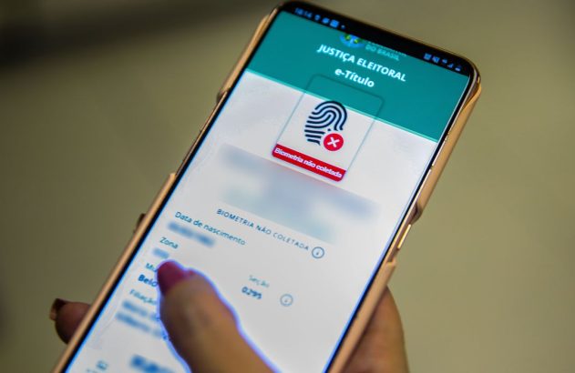 Pessoa segura celular com app e-Título da Justiça Eleitoral exibindo aviso "Biometria não coletada".