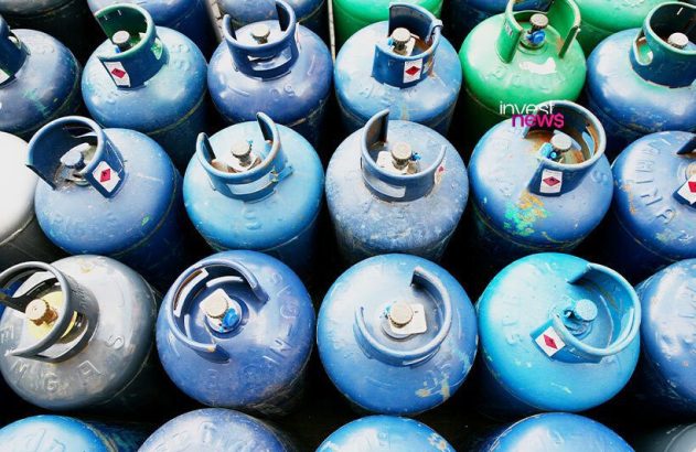 Dezenas de botijões de gás azuis e verdes, dispostos em fileiras e vistos de cima, mostrando válvulas e adesivos.