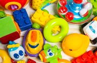 Uma variedade de brinquedos de bebê e criança em cores vibrantes, como blocos de montar, pato e carrinhos.