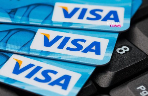 Três cartões Visa azuis empilhados sobre um teclado.