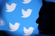Silhueta de pessoa olhando para tela azul com vários logos brancos do Twitter.