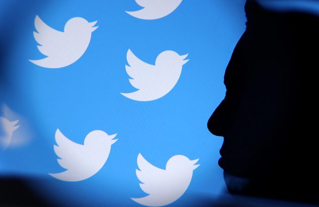 Silhueta de pessoa olhando para tela azul com vários logos brancos do Twitter.