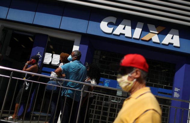Fila de pessoas com máscaras em frente à agência da Caixa Econômica Federal.