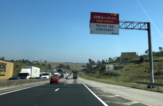 Rodovia com tráfego lento e letreiro da CCR NovaDutra: "BEM-VINDO - TRECHO SOB CONCESSÃO".