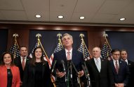 Kevin McCarthy fala em coletiva de imprensa com colegas e bandeiras dos EUA ao fundo.