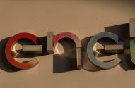 Letreiro Enel com letras 3D coloridas (vermelho, azul, verde) e sombras fortes em uma parede clara.