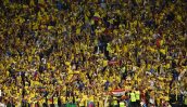 Torcedores do Equador com camisas amarelas e bandeiras celebram em um estádio lotado.