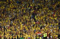 Torcedores do Equador com camisas amarelas e bandeiras celebram em um estádio lotado.