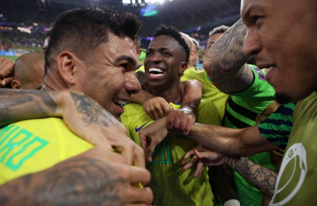 Jogadores da seleção brasileira, incluindo Vini Jr. e Casemiro, celebrando e sorrindo abraçados em campo.