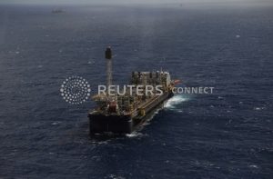 Navio-plataforma de petróleo e gás flutuando em mar aberto, com outras embarcações ao longe.