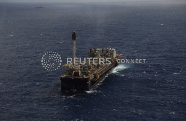 Navio-plataforma de petróleo e gás flutuando em mar aberto, com outras embarcações ao longe.