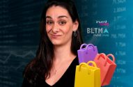 Mulher com expressão levemente divertida, três sacolas de compras coloridas e dados financeiros ao fundo.