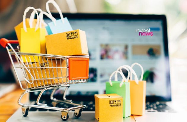 Compras online: mini carrinho, sacolas e caixas em laptop com site de e-commerce e logo Invest News.