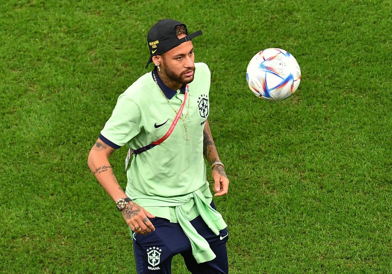 Neymar Jr. em campo, olhando para uma bola de futebol que flutua no ar.