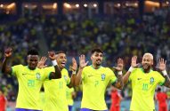 Quatro jogadores do Brasil de amarelo celebram, sorrindo e com mãos levantadas, em estádio com torcida.