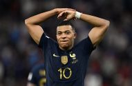 Kylian Mbappé, jogador da França, camisa 10, com as mãos acima da cabeça e expressão séria em jogo de futebol.
