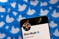 Celular exibe perfil de Elon Musk no Twitter com foto, nome, @elonmusk e selo verificado. Fundo de logos do pássaro.