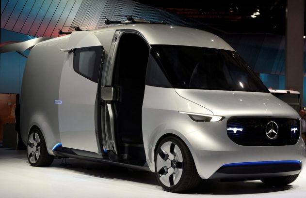 Van conceito Mercedes-Benz prateada em exposição, porta lateral aberta, drones no teto, iluminação azul.