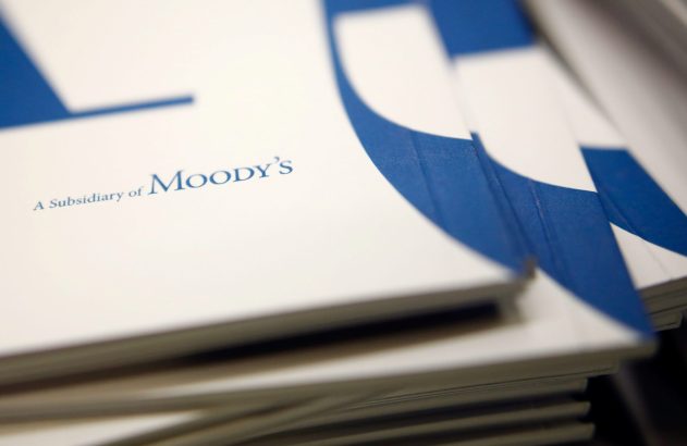 Pilhas de documentos brancos e azuis com a frase "A Subsidiary of Moody's" visível.
