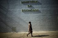 Pessoa descalça com cobertor passa em frente ao Ministério da Economia.