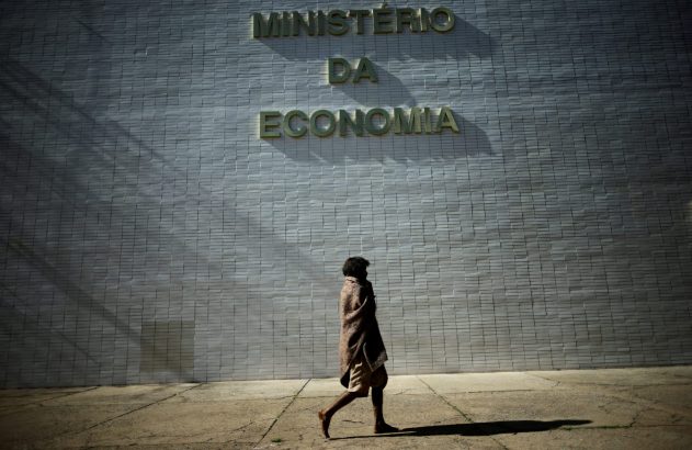 Pessoa descalça com cobertor passa em frente ao Ministério da Economia.