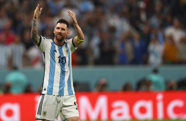 Lionel Messi, com camisa da Argentina, sorrindo e acenando em um estádio.