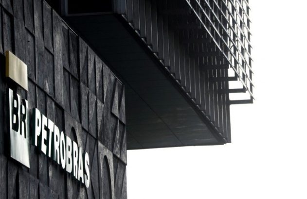 Edifício Petrobras: logo BR PETROBRAS na fachada escura e texturizada. Estrutura superior de grades contra céu branco.