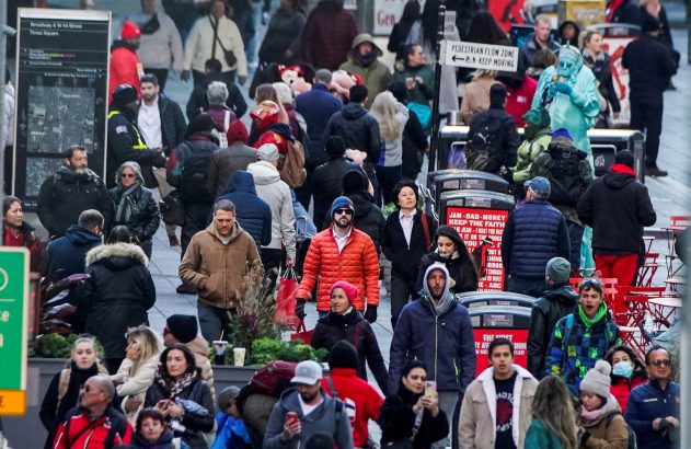Multidão de pessoas em uma rua movimentada de Nova York. Um artista vestido como Estátua da Liberdade visível.