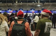 Pessoas com chapéus de Papai Noel e malas em uma área de check-in movimentada da Delta.