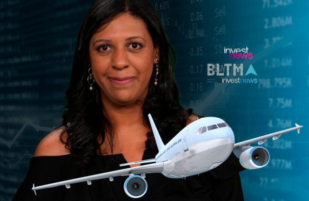 Mulher sorridente com modelo de avião em frente a painel financeiro Investnews.