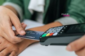 Mão inserindo cartão de crédito em terminal de pagamento.