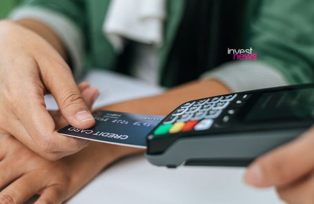 Mão inserindo cartão de crédito em terminal de pagamento.